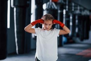 retrato de menina em roupas esportivas que está na academia tem dia de exercício. concepção de boxe foto