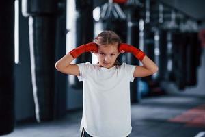 retrato de menina em roupas esportivas que está na academia tem dia de exercício. concepção de boxe foto