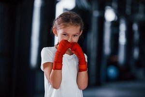 retrato de menina em roupas esportivas que está na academia tem dia de exercício. concepção de boxe foto