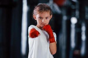 retrato de menina em roupas esportivas que está na academia tem dia de exercício. concepção de boxe foto