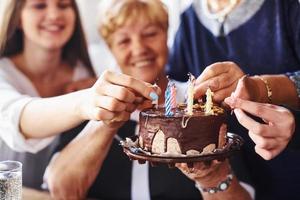 mulher sênior com família e amigos comemorando um aniversário dentro de casa foto