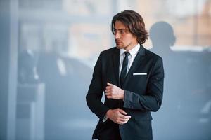 retrato do jovem empresário bonito de terno preto e gravata foto