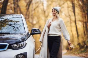 curtindo a natureza. menina tem viagem de outono de carro. automóvel novo e moderno na floresta foto