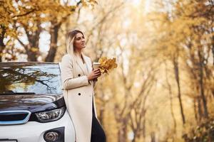 menina tem viagem de outono de carro. automóvel novo e moderno na floresta foto