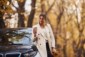 menina tem viagem de outono de carro. automóvel novo e moderno na floresta foto