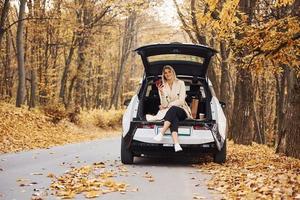 menina senta-se na parte de trás do carro. automóvel novo e moderno na floresta foto