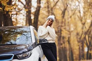 menina tem viagem de outono de carro. automóvel novo e moderno na floresta foto