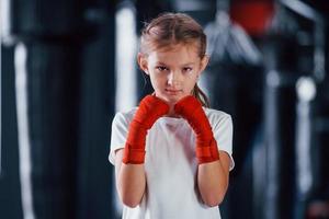 retrato de menina em roupas esportivas que está na academia tem dia de exercício. concepção de boxe foto