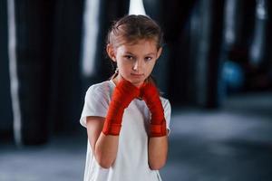 retrato de menina em roupas esportivas que está na academia tem dia de exercício. concepção de boxe foto