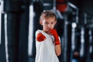 retrato de menina em roupas esportivas que está na academia tem dia de exercício. concepção de boxe foto