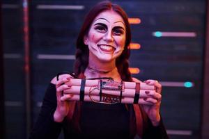 retrato de mulher que está na festa temática de halloween em maquiagem assustadora e fantasia com bomba nas mãos foto