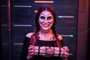 retrato de mulher que está na festa temática de halloween em maquiagem assustadora e fantasia com bomba nas mãos foto