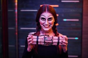 retrato de mulher que está na festa temática de halloween em maquiagem assustadora e fantasia com bomba nas mãos foto