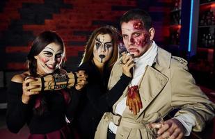 amigos com bomba nas mãos está na festa temática de halloween em maquiagem e fantasias assustadoras foto