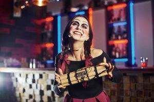 retrato de mulher que está na festa temática de halloween em maquiagem assustadora e fantasia com bomba nas mãos foto