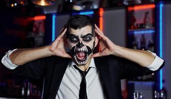 retrato do homem que está na festa temática de halloween em maquiagem e fantasia de esqueleto assustador foto