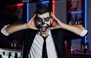 retrato do homem que está na festa temática de halloween em maquiagem e fantasia de esqueleto assustador foto