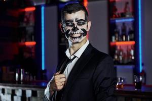 retrato do homem que está na festa temática de halloween em maquiagem e fantasia de esqueleto assustador foto