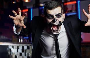 gritando para a câmera. retrato do homem que está na festa temática de halloween em maquiagem e fantasia de esqueleto assustador foto