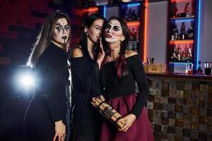 três amigas estão na festa temática de halloween com maquiagem e fantasias assustadoras foto