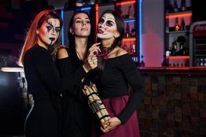 três amigas estão na festa temática de halloween com maquiagem e fantasias assustadoras foto