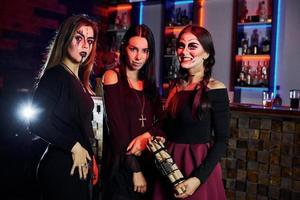 três amigas estão na festa temática de halloween com maquiagem e fantasias assustadoras foto