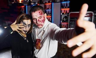 posando para a câmera. amigos está na festa temática de halloween em maquiagem e fantasias assustadoras foto