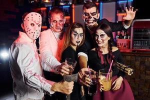 posando para a câmera. amigos está na festa temática de halloween em maquiagem e fantasias assustadoras foto