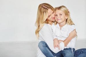 mãe com sua filha se divertem juntos no estúdio com fundo branco foto