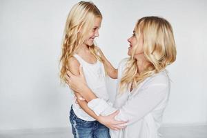 mãe com sua filha se divertem juntos no estúdio com fundo branco foto