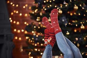 mãe com sua filhinha deitada no chão dentro de casa em roupas festivas nas férias de natal foto