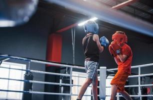 dois meninos em equipamento de proteção lutam e lutam no ringue de boxe foto