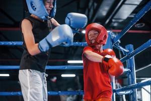 dois meninos em equipamento de proteção lutam e lutam no ringue de boxe foto
