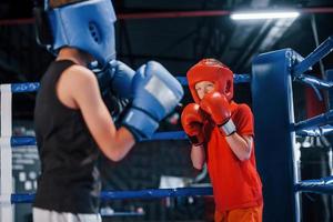 dois meninos em equipamento de proteção lutam e lutam no ringue de boxe foto