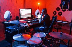 jovem engenheiro de som trabalhando e mixando música dentro de casa no estúdio foto