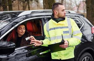 policial masculino de uniforme verde aceita suborno de mulher no carro foto
