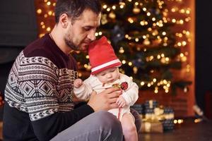 pai com seu filho juntos no quarto decorado de natal foto