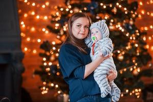 mãe com seu filho juntos no quarto decorado de natal foto