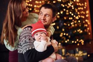 pai e mãe com seu filho juntos no quarto decorado de natal foto