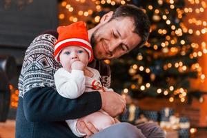 pai com seu filho juntos no quarto decorado de natal foto