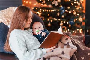 mãe com seu filho juntos no quarto decorado de natal foto