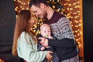 pai e mãe com seu filho juntos no quarto decorado de natal foto