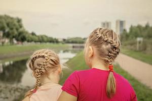 irmãs de duas meninas sentam-se abraçadas na ponte do parque. Apoio, suporte foto