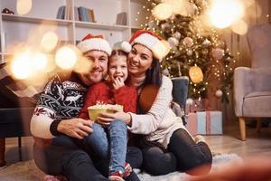 família feliz dentro de casa com chapéus de natal se divertem juntos e comemoram o ano novo foto
