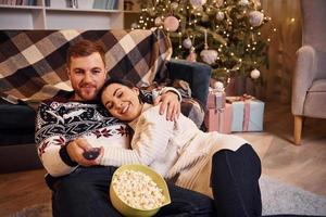 jovem casal dentro de casa no quarto decorado de natal se divertem juntos e comemoram o ano novo foto