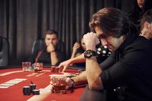 grupo de jovens elegantes que jogam pôquer no cassino juntos foto