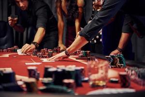 pessoas em roupas elegantes em pé e jogando pôquer no cassino juntos foto