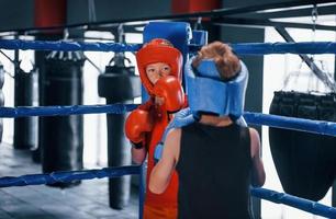 dois meninos em equipamento de proteção lutam e lutam no ringue de boxe foto