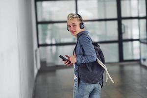 jovem estudante em roupas casuais caminha dentro de casa com mochila foto