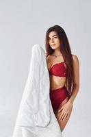 mulher de cueca vermelha cobrindo o corpo com uma toalha no estúdio contra fundo branco foto